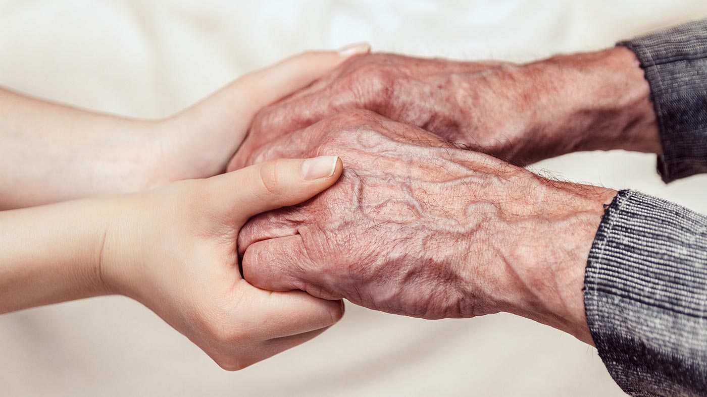 Hände eines alten Mannes und einer jungen Frau halten einander vertrauensvoll
