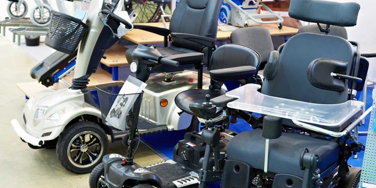 Elektrorollstühle und E-Scooter stehen ausgestellt in Reihe