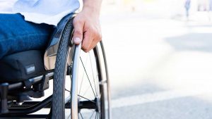 Mann im Rollstuhl umfasst die Greifringe seines Rollstuhl